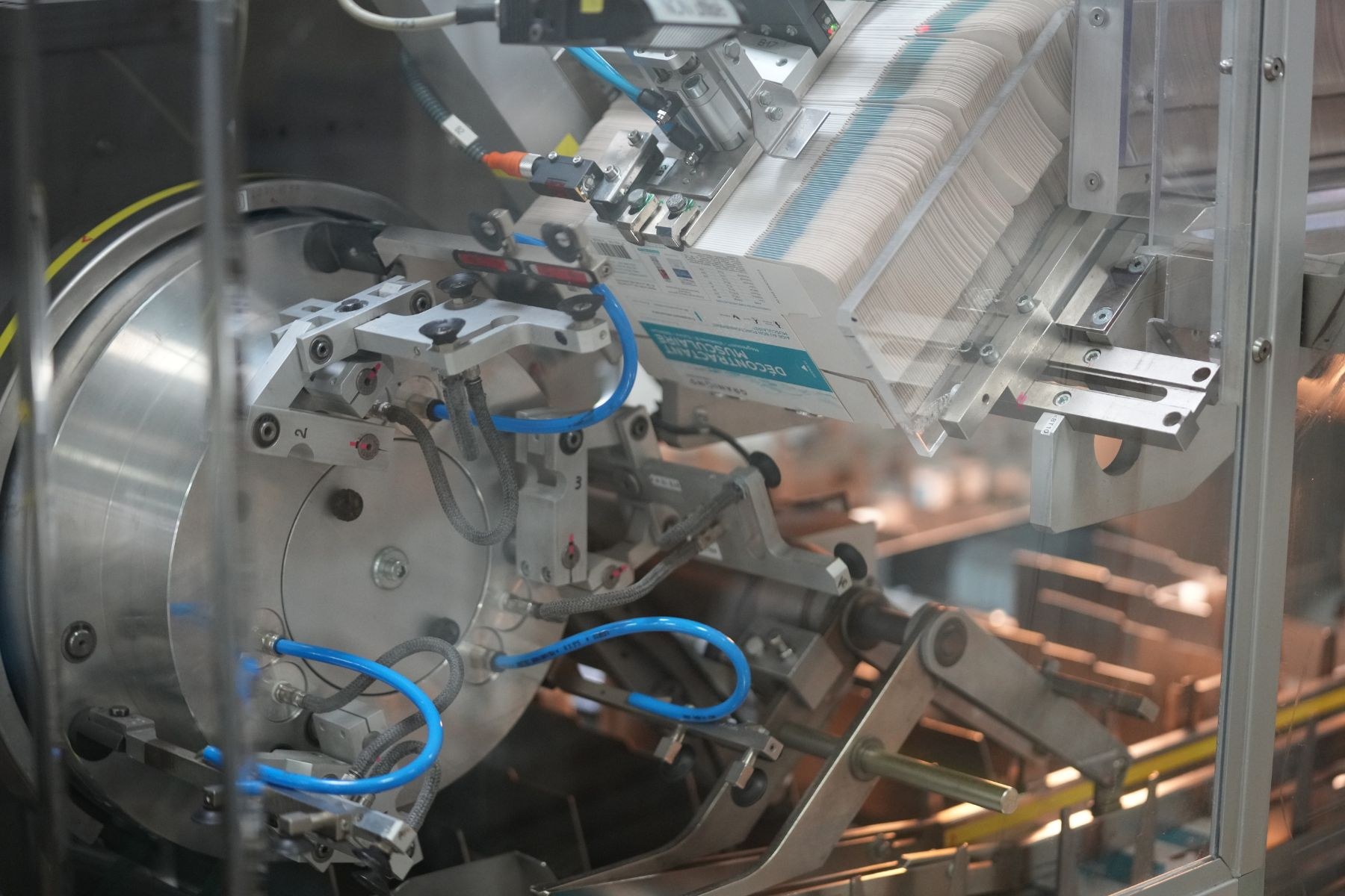 Automatisierte Verpackungsmaschine auf einem Fabriktisch mit leicht unscharfen Hintergrundobjekten.