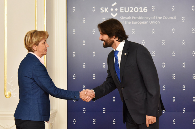 Bundeskanzlerin Angela Merkel und Joachim Gauck, die sich vor einem Banner mit der Aufschrift 'EU-Gipfel' die Hände schütteln, beide lächelnd.