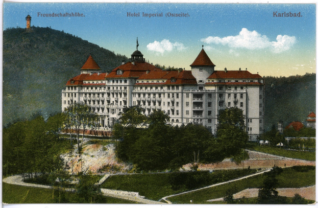 Alte Ansichtskarte des Hotel Imperial in Karlsbad, Deutschland, die ein großes Gebäude mit Fenstern zeigt, umgeben von Bäumen, Pflanzen, Gras, einem Weg, einer Baumgruppe, Hügeln und einem bewölkten Himmel, mit Text oben.
