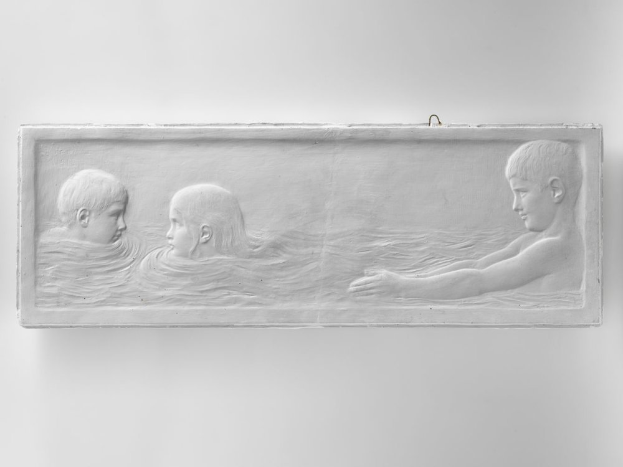 Drei Kinder beim Schwimmen in einem Wasserbecken, mit einer Wand im Hintergrund, dargestellt auf einem Schwarz-Weiß-Foto.