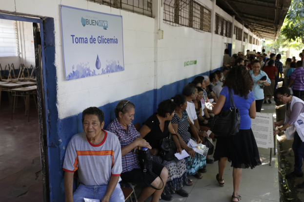 Große Gruppe von Menschen an Tischen unter einem Zelt auf dem Oktoberfest in München, Deutschland, mit Taschen und Gegenständen auf den Tischen, festlicher Hintergrund von Zelten, Lichtern und Flaggen.