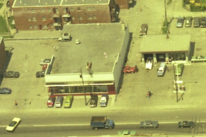 Eine Luftaufnahme einer Stadt mit zahlreichen Autos um Gebäude herum und einigen Autos auf den Straßen.