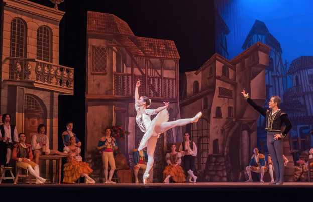 Zwei Tänzer performen auf einer Bühne im Royal Opera House in London, während das Publikum zuschaut.