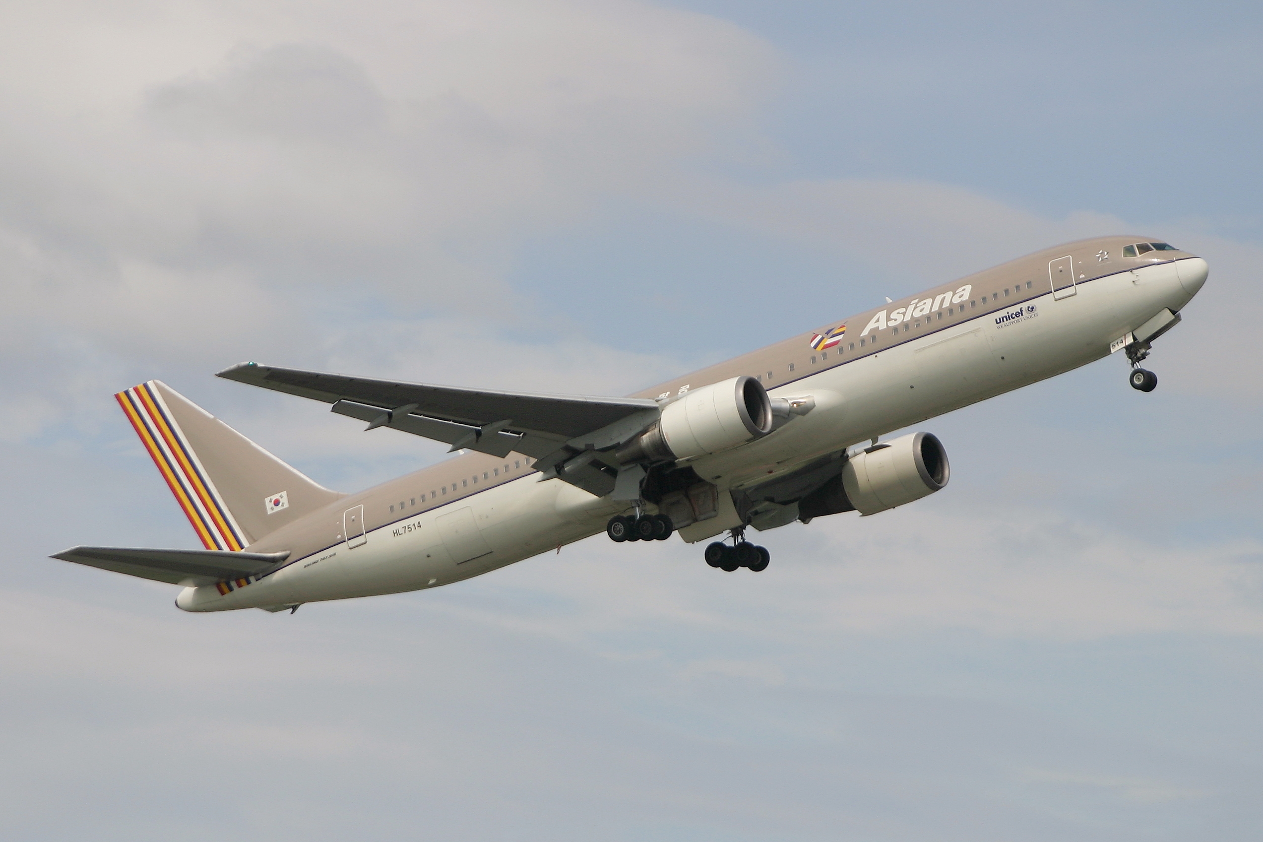 Ein Airbus A330-300 der Asia Airlines fliegt am Himmel mit weißen, flauschigen Wolken im Hintergrund, mit ausgebreiteten Flügeln und sichtbaren Triebwerken.