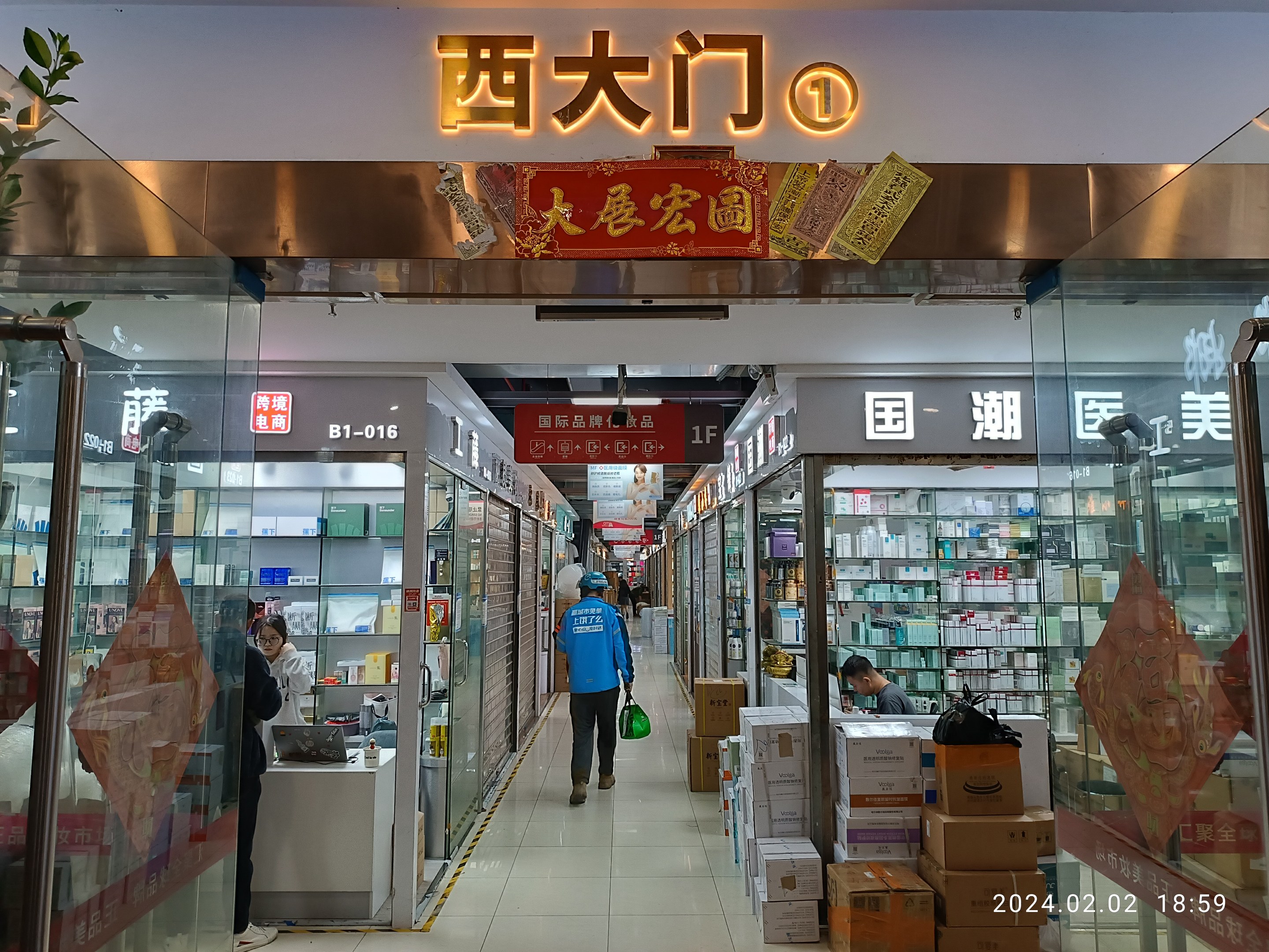 Innenansicht einer chinesischen Apotheke mit Glaswänden, einer Pflanze links, Regalen mit Artikeln, verstreuten Kartons und einer Namensschild oben.