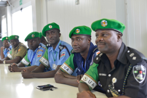 Gruppe von Polizeibeamten, die an einem Tisch sitzen, mit Mobiltelefonen und anderen Gegenst├Ąnden auf dem Tisch, in einem Raum mit Fenstern und Deckenleuchten.