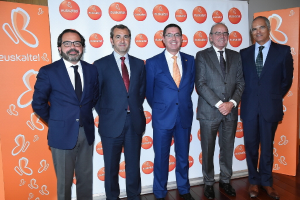 Eine Gruppe von Männern, die für ein Foto posieren, mit Schildern im Hintergrund, die den Namen einer Organisation tragen.