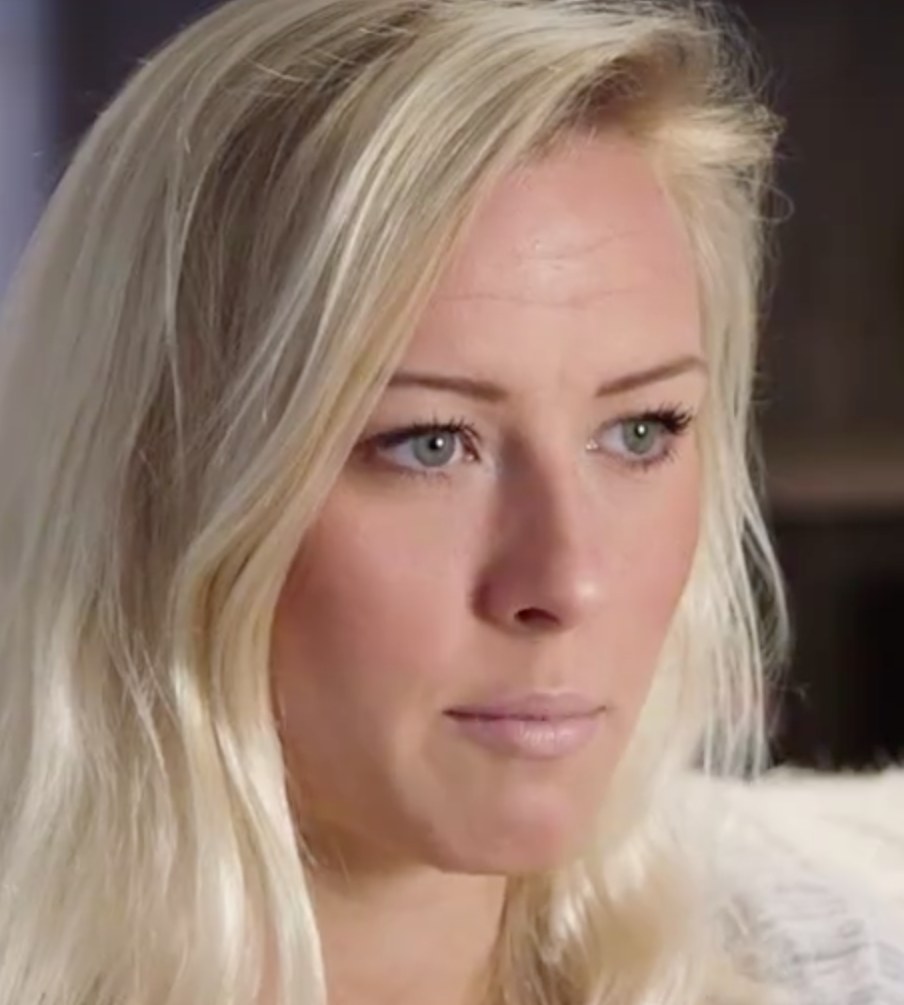 Blonde Frau mit blauen Augen in Not, Hintergrund unscharf, suggeriert erzwungenen Abgang von einer Show.