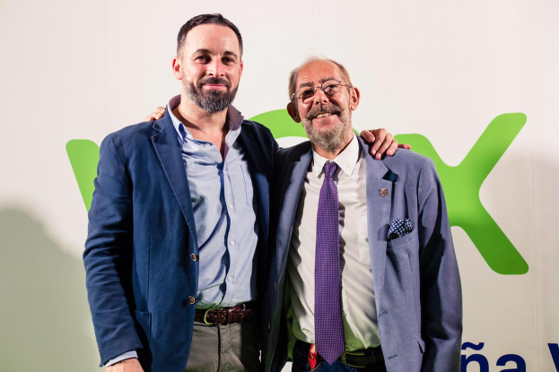 Zwei Männer in Anzügen lächeln nebeneinander vor einer Wand, wobei der Mann rechts eine Brille trägt; ein Schild im Hintergrund trägt die Aufschrift "Vodafone und Vodacom verkünden Partnerschaft."