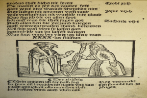 Ein Blatt Papier mit gedrucktem Text in einer fremden Sprache, mit zwei Männern im Hintergrund, möglicherweise aus einem Lehrbuch.