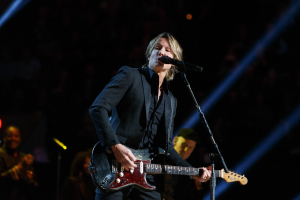 Keith Urban performs auf der Bühne im Joint im Hard Rock Hotel & Casino in Las Vegas, spielt Gitarre mit einem Mikrofon vor sich und Bandmitgliedern im Hintergrund bei gedämpfter Beleuchtung.