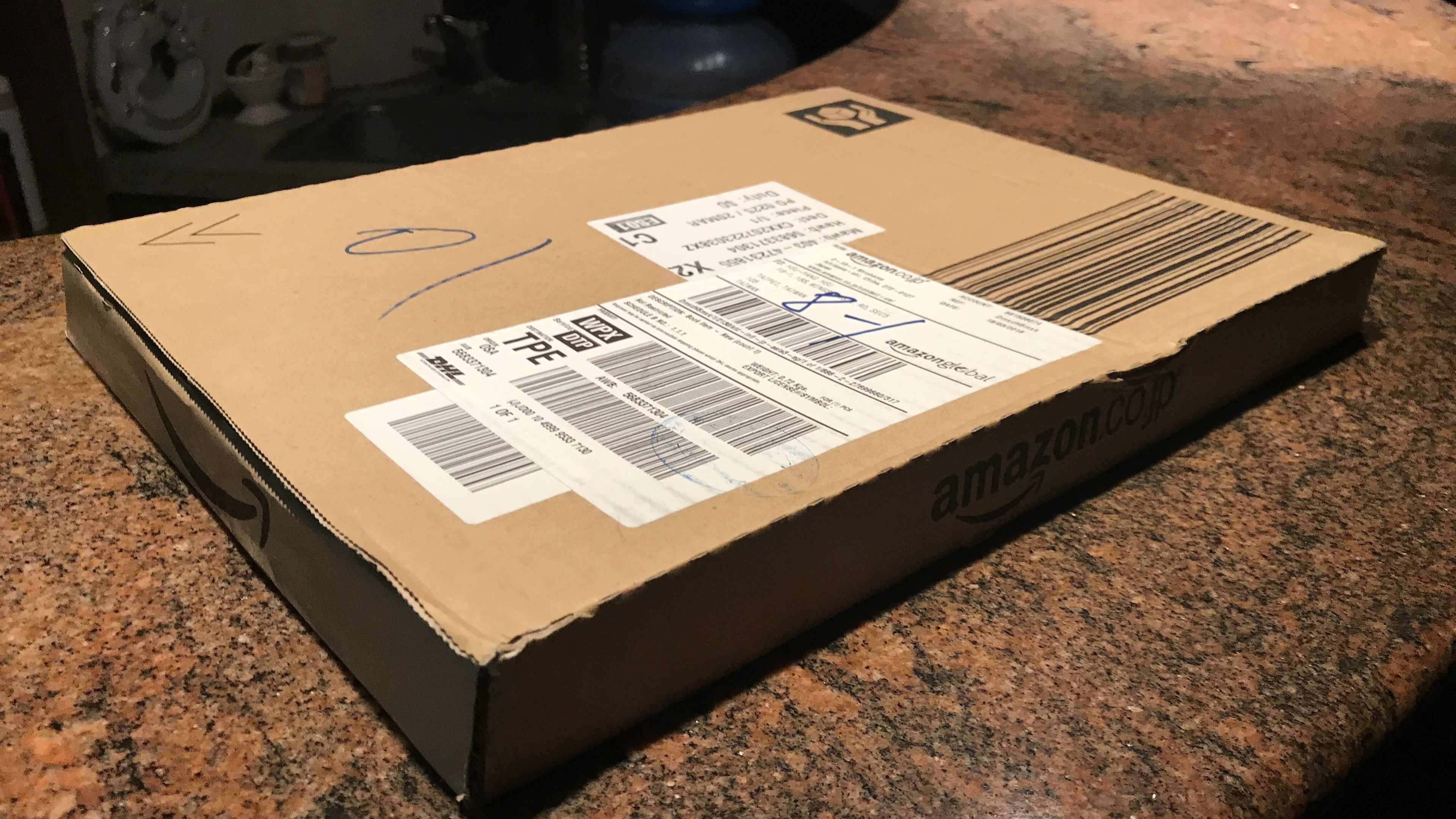 Kartonbox mit der Aufschrift 'Amazon Prime Day' auf einer Arbeitsplatte stehend mit ein paar Gegenständen im Hintergrund.