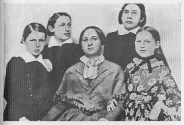 Ein Schwarz-Weiß-Foto einer vielfältigen Gruppe von Frauen, mit einer sitzenden Frau in der Mitte und dem Text "Die Frauenwahlrechtsbewegung" unten.