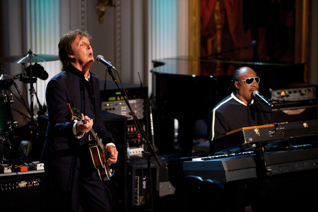 Paul McCartney und Stevie Wonder auf der Bühne bei den Grammys, mit McCartney an der Gitarre und singend, und Wonder mit Schutzbrille am Piano.