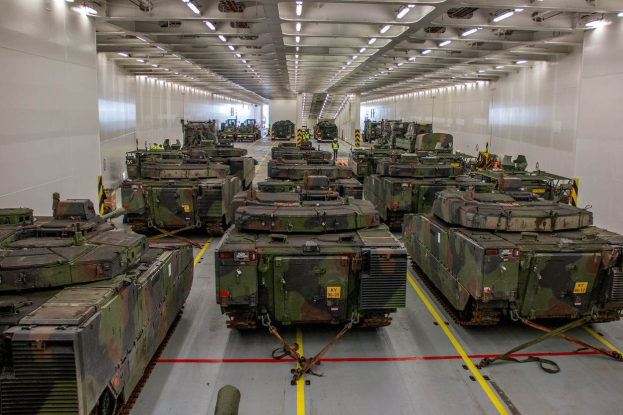 Ein grosser Militaraerraum mit Reihen von Militaraerfaehrzeugen, Wänden auf beiden Seiten und Deckenbeleuchtung.