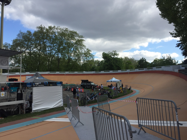 Gruppe von Radfahrern auf einer Schmutz-BMX-Strecke bei den UCI-BMX-Weltmeisterschaften 2018, mit Zuschauern, Zelten und Fahrzeugen im Hintergrund.