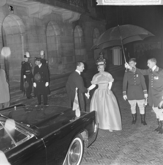 Schwarzes und weißes Foto von Queen Elizabeth II und Prinz Philip, Duke of Edinburgh, bei der Ankunft in Buckingham Palace in formeller Kleidung, wobei die Queen einen Strauß hält und der Duke einen Schirm.