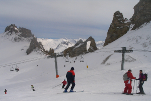 Menschen in Pullovern fahren auf dem Eis Ski, mit einer Seilbahn, Bergen und einem bewölkten Himmel im Hintergrund.