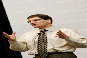 Eine Person steht vor einer Sponsorwand und trägt Kleidung und eine Brille.