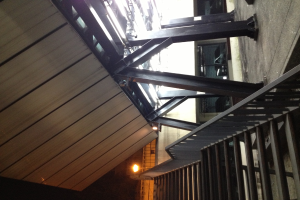 Treppen mit Geländern in der unteren rechten Ecke, Säulen auf der rechten Seite des Bodens, Autos in Gebäuden hinter den Säulen und Lampen auf der linken Seite mit sichtbarer Decke.