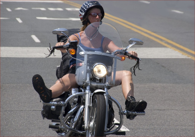 Frau fährt Fahrrad auf Straße mit schwarzem Helm