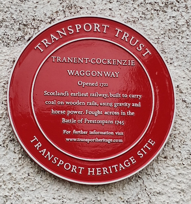 Rote runde Plakette an einem Gebäude mit der Aufschrift "Transport Trust".