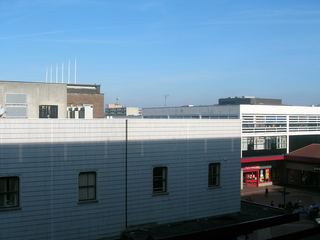 Eine Straßenszene mit Gebäuden und Geschäften, die einige Menschen zwischen ihnen zeigen.