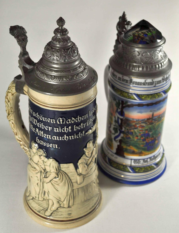 Zwei deutsche Bierhumpen mit detaillierten Designs und Texten, nebeneinander auf einer weißen Oberfläche gestellt.