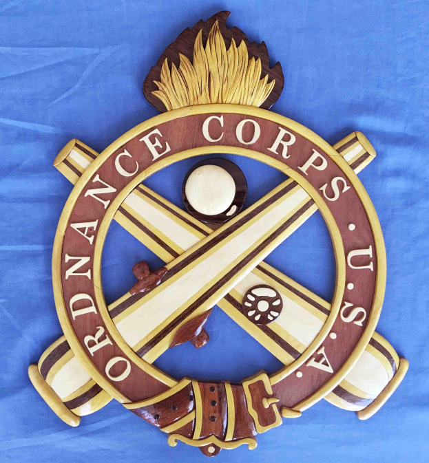 Holzschild mit "Ordnance Corps"-Text, das ein geschnitztes weißes Stern auf einem marineblauen Hintergrund mit goldener Umrandung zeigt, auf blauem Stoff montiert.