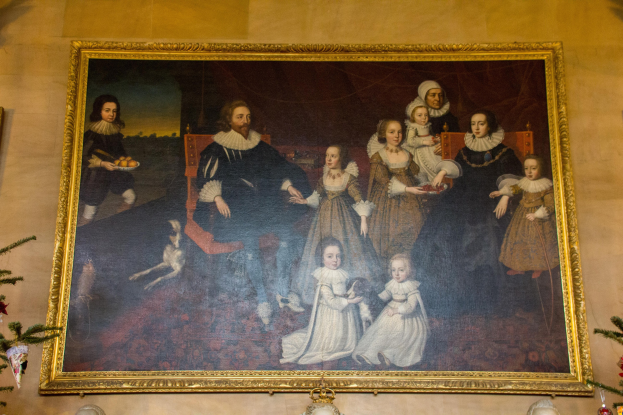 Ein gerahmtes Bild einer Familie mit einem Weihnachtsbaum im Hintergrund, flankiert von zwei Fotorahmen, mit dekorativen Elementen unten.