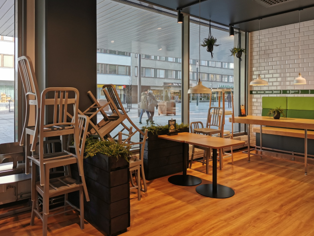 Ein Berliner Restaurant mit Holztischen und -stühlen in der Nähe eines großen Fensters, das eine Straßenszene im Freien zeigt.