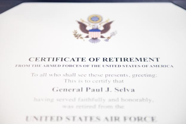 Rahmenurkunde zur Ruhestandsversetzung von der United States Air Force mit blauer Einfassung, die ein zentrales Sternsymbol innerhalb eines Lorbeerkranzes und ein 'Ruhestand'-Banner auf einem Schild-Logo zeigt, alles in schwarzer Tinte.