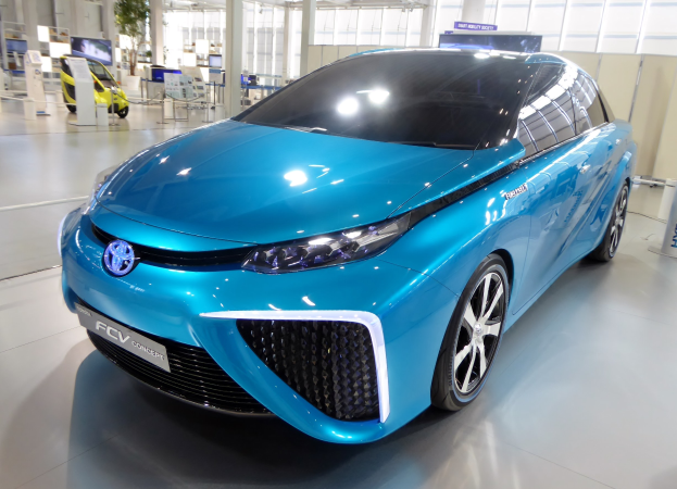 Ein blauer Toyota FT-1 Konzeptwagen auf der Internationalen Automobil-Ausstellung in Frankfurt, umgeben von anderen Autos, Tafeln, Säulen, Lichtern und verschiedenen Gegenständen.