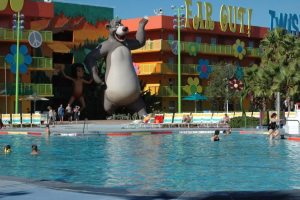 Ein Schwimmbad mit blauem Wasser und schwimmenden Menschen, mit entfernten Cartoons und Stangen im Hintergrund.