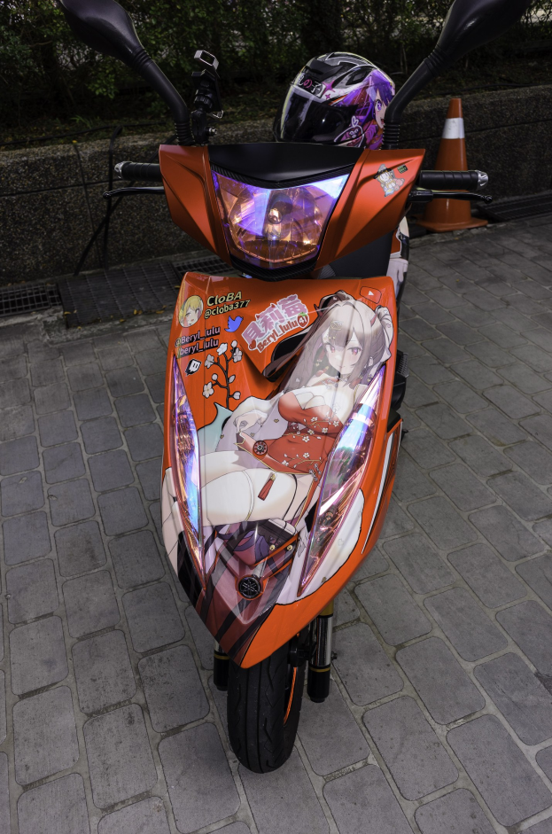 Ein oranger Scooter mit einem Helm darauf auf einer Straße geparkt, mit einem Verkehrskegel, einer Wand und Bäumen im Hintergrund.
